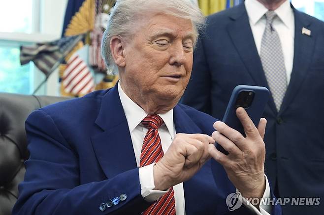 집무실 문답 중 전화가 울리자 벨 소리를 무음으로 바꾸는 트럼프 [워싱턴 AP=연합뉴스. 재판매 및 DB 금지]