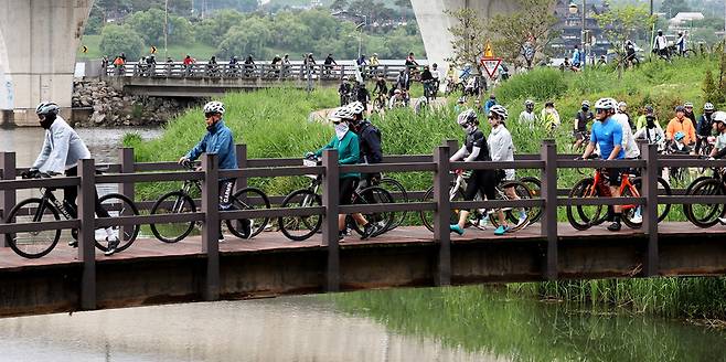 ▲경기친환경자전거페스티벌에 참가한 라이더들이 잠시 자전거에서 내려 부교를 건너고 있다. 2000여명이 참가한 가운데 챌린지와 패밀리 코스를 나눠 달렸다.&nbsp;