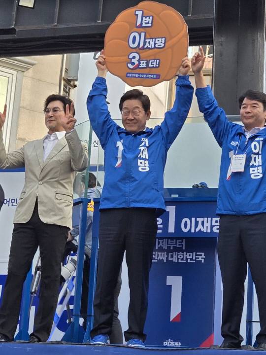 25일 저녁 충남 천안 신부동 신부문화거리에서 가진 유세에서 이재명 더불어민주당 후보(가운데)가 123 캠페인을 홍보하는 호두모양 피켓을 들어보이고 있다. 박하늘 기자