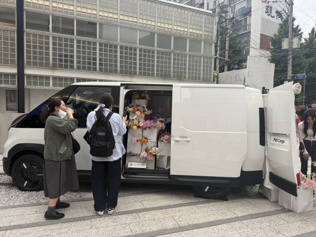 꽃집으로 꾸며진 기아 PV5 카고 모델을 방문객들이 살펴보고 있다.