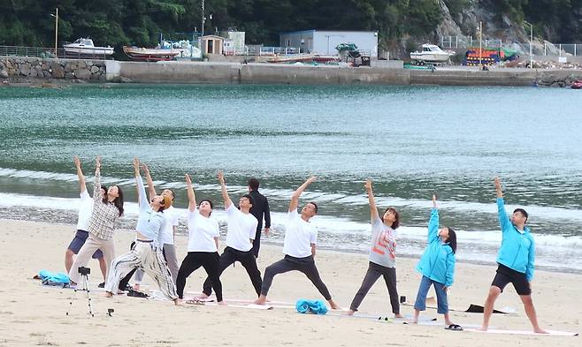 지난해 10월 전국 처음으로 남해군 미조면 송남마을에서 진행된 ‘도시 탈출! 경남 4도3어촌’ 체험 프로그램 참가자들이 해변 요가를 함께 하고 있다. 경남도 제공