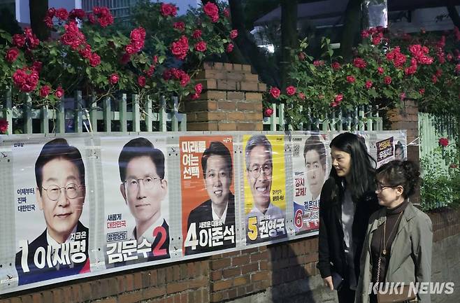 25일 대전광역시 서구 둔산동의 한 아파트 담장에 만개한 장미꽃 아래 유권자들이 제21대 대통령 선거 벽보를 살펴보고 있다.&nbsp;