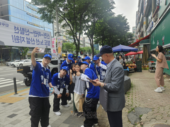 더불어민주당 2030 청년 선거운동원인 시너지유세단장 구구(앞쪽)씨가 21일 경기 광명시에서 선거유세 무대를 마친 뒤 시민의 요청으로 인증사진을 다같이 찍고 있다. 박상연 기자