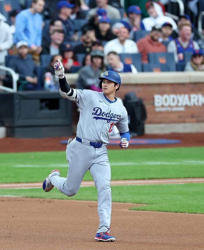 LA 다저스 오타니 쇼헤이가 26일(한국시각) 시티필드에서 열린 뉴욕 메츠전에서 1회초 우월 솔로포를 날린 뒤 오른손을 치켜들고 베이스를 돌고 있다. AFP연합뉴스