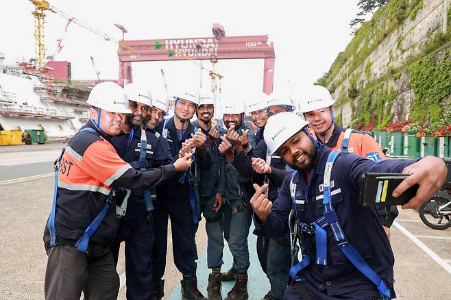 지난 23일 HD현대중공업 건조2부 선체1팀에서 일하는 내·외국인 근로자들이 선박 내부 설비 설치 작업을 마친 뒤 화기애애하게 셀카를 찍고 있다. 세계적인 경쟁력을 갖췄지만 인력 확보에 어려움을 겪는 우리 조선소는 대안으로 외국인 근로자의 실력을 기르고 빠르게 정착시키는 데 공을 들이고 있다. /HD현대중공업