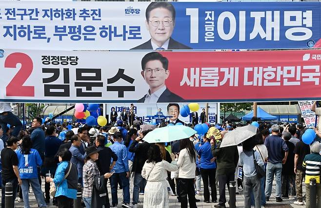 이재명 더불어민주당 대선 후보가 21일 인천 부평구 부평역 북광장에서 열린 집중 유세에 참석해 지지를 호소하고 있는 가운데 김문수 국민의힘 대선 후보의 현수막이 보이고 있다./한국경제