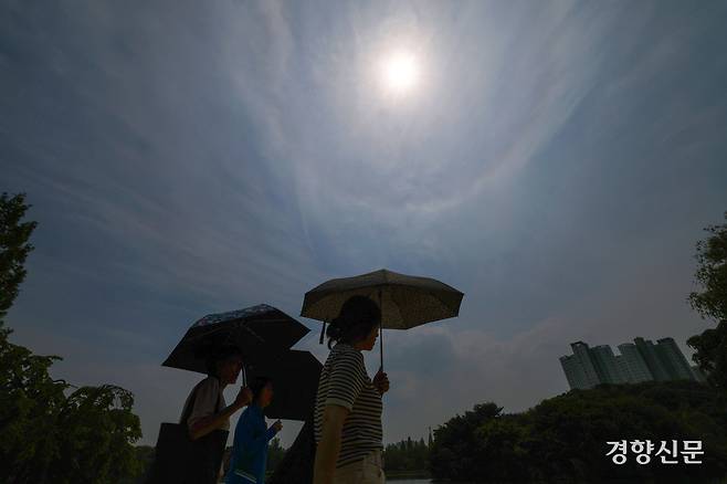 26일 경기 고양시 일산호수공원에서 시민들이 양산을 쓰고 걸어가고 있다. 권도현 기자