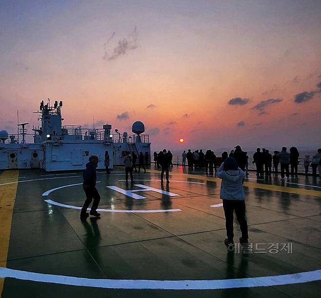 울릉크루즈의  뉴시다오펄호 승객들이 선상에서 겨울 해넘이를 감상하며 사진을 찍고 있다(사진=김성권 기자)