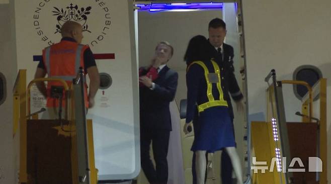 [AP/뉴시스] 비디오 사진으로 25일 저녁 하노이 공항에 도착한 프랑스의 마크롱 대통령이 내릴 채비를 하다 빨간 소매에 밀침을 당하고 있다