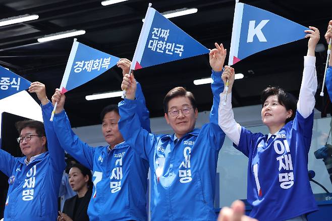 더불어민주당 이재명 대선 후보가 26일 수원시 팔달구 팔달문 영동시장에서 열린 집중 유세에서 "진짜 대한민국"이라고 쓰인 손깃발을 들고 인사하고 있다. 연합뉴스