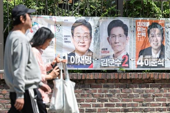 6·3 대선 사전 투표일을 나흘 앞둔 25일 대선 벽보가 붙어 있는 서울 종로구 동숭동 예술가의집 담장 앞을 시민들이 지나가고 있다. 사전 투표는 29~30일 오전 6시부터 오후 6시까지 진행된다. 뉴스1