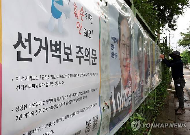 '선거 벽보 훼손 안 돼요' (전주=연합뉴스) 나보배 기자 = 제21대 대통령 선거 벽보 부착을 시작한 15일 전북선거관리위원회 관계자가 전주시 완산구 효자동의 한 아파트 입구에 후보자 벽보를 붙이고 있다. 2025.5.15 warm@yna.co.kr