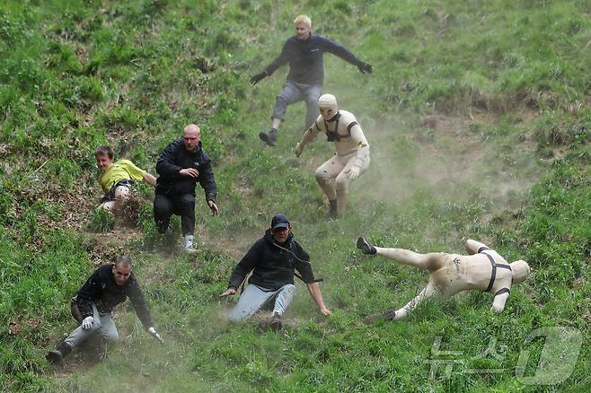 26일(현지시간) 영국 브록웍스의 쿠퍼스 힐에서 열린 '구르는 치즈 잡기' 대회에서 참가자들이 치즈를 쫒아 언덕을 내려가다 넘어지고 있다. ⓒ 로이터=뉴스1