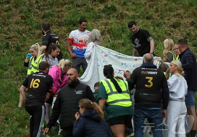 26일(현지시간) 영국 브록웍스의 쿠퍼스 힐에서 열린 '구르는 치즈 잡기' 대회에서 부상당한 참가자가 치료를 받고 있다. ⓒ 로이터=뉴스1