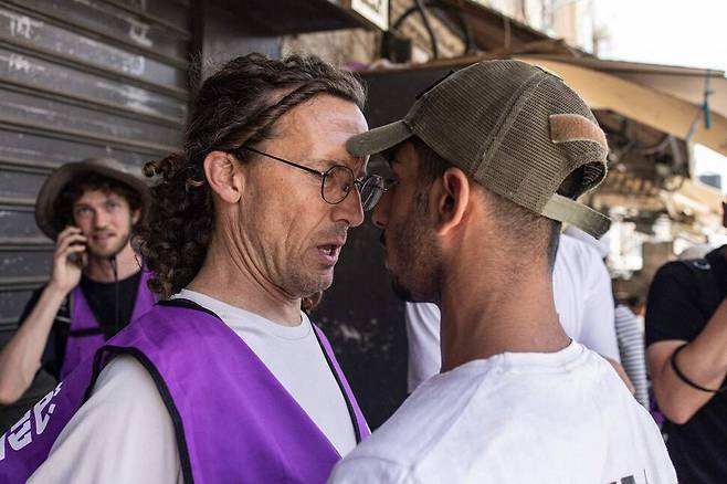 26일(현지시각) 예루살렘 구시가지에서 시위에 참여 중인 이스라엘 우익 청년과 폭력 시위를 방어하기 위해 자원봉사 중인 보라색 조끼를 입은 반전 단체 활동가가 대립하고 있다. 예루살렘/AFP 연합뉴스