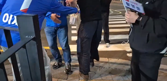 23일 부산 광안리에서 검은색 상의를 입은 한 청년(가운데)이 이재명 더불어민주당 대선 후보 지원 유세를 하고 있던 박주민(왼쪽) 민주당 의원을 어디론가 끌고 가려 하고 있다. '박주민TV' 유튜브 영상 캡처