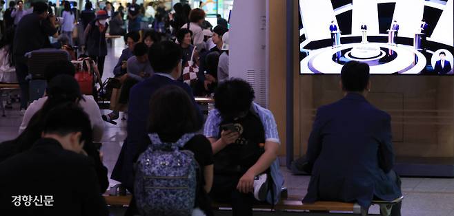 마지막 TV토론 보는 시민들 27일 서울역을 찾은 시민들 너머 화면에서 21대 대통령 선거 이재명 더불어민주당 후보·김문수 국민의힘 후보·이준석 개혁신당 후보·권영국 민주노동당 후보가 하는 마지막 TV토론이 생중계되고 있다. 이준헌 기자 heon@kyunghyang.com