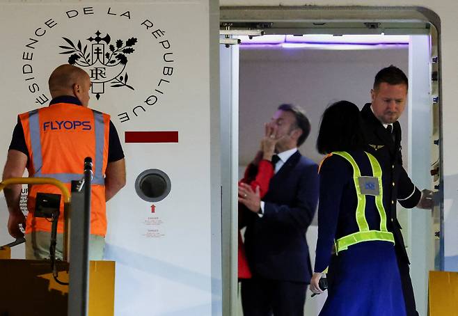 에마뉘엘 마크롱 프랑스 대통령이 25일(현지시간) 베트남 하노이 공항에 도착했을 당시 전용기 내부에서 부인 브리지트 마크롱 영상에게 얼굴을 맞는 모습. [로이터]