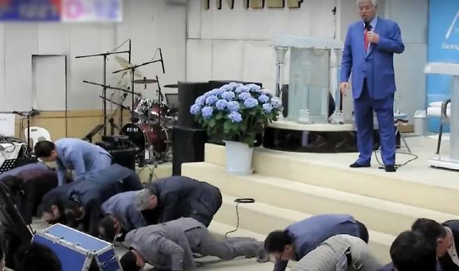 전광훈 목사가 “(집회 참여자 할당 인원을 데려오지 못한 사람은)대가리를 박는다, 실시”라고 지시하고 교구 지역 대표들이 머리를 바닥에 대고 엎드려뻗쳐 자세를 하고 있다. [전광훈TV 갈무리]