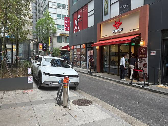 서울 서초구 일대 한 식당 골목가. 주차 관리인이 자리를 비운 사이 한 전기차가 인도에 차를 세워뒀다. /한영원 기자