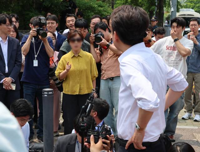 이준석 개혁신당 대선 후보가 28일 서울 여의도공원에서 유세를 마치고 백브리핑을 하던 중 한 시민으로부터 전날 TV토론회에서 여성 신체에 대한 폭력적 표현을 언급한 것과 관련해 항의받고 있다. 연합뉴스.