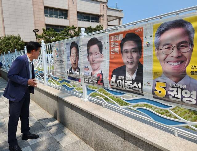 한 시민이 27일 부산 동구 부산역 뒤편 벽에 부착된 선거벽보를 보고 있다.