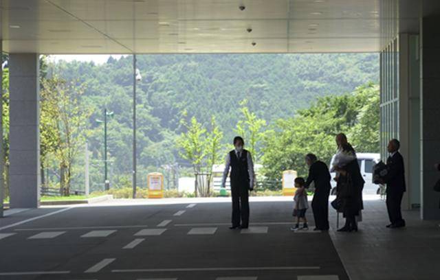 일본의 한 화장장에서 시설 직원(맨 왼쪽)이 유골함을 든 유가족들을 배웅하고 있다.