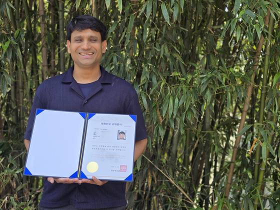 지난 20일 한국 국적을 취득한 아이치 샤티야브러타(41)씨가 부산대 교정에서 귀화증서를 들고 서 있다. 이은지 기자