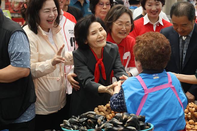 Seol Nan-young, wife of conservative People Power Party presidential candidate Kim Moon-soo, holds the hands of a merchant working at a local market in Pyeongtaek in Gyeonggi on May 25. [PEOPLE POWER PARTY]