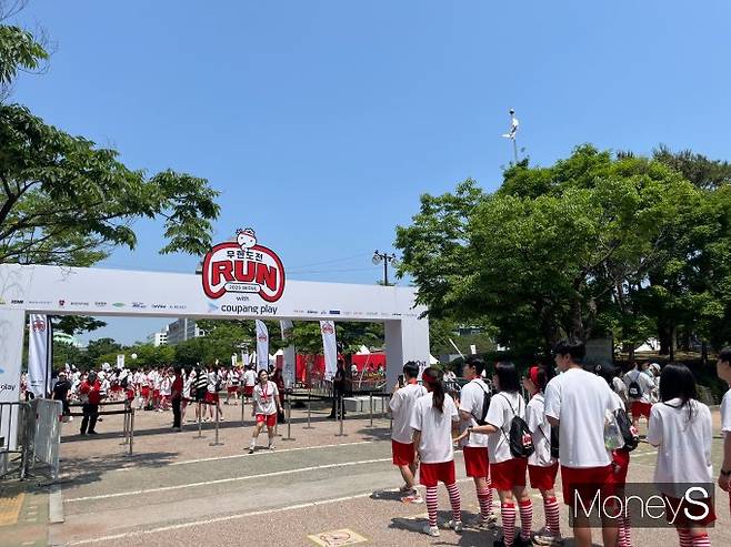 지난 25일 ‘무한도전 Run with 쿠팡플레이’ 행사에서 참가자들이 서울 영등포구 여의도공원 입구 앞에서 줄을 서 입장하고 있으며, 일부는 무한도전 로고 앞에서 인증샷을 남기고 있다. /사진=김대영 기자