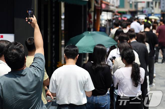 제21대 대통령선거 사전투표 첫 날인 29일 서울 중구 소공동주민센터에 마련된 투표소에서 직장인들이 점심시간 투표를 위해 대기하며 길게 늘어선 투표 인파를 스마트폰에 담고 있다. ⓒ News1 오대일 기자
