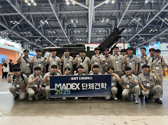 SNT다이내믹스 입차 3년차 미만 이공계 엔지니어들이 부산 벡스코에서 열리는 국제해양방위산업전 'MADEX 2025'에 단체견학 후 기념사진을 찍고 있다. SNT다이내믹스 제공
