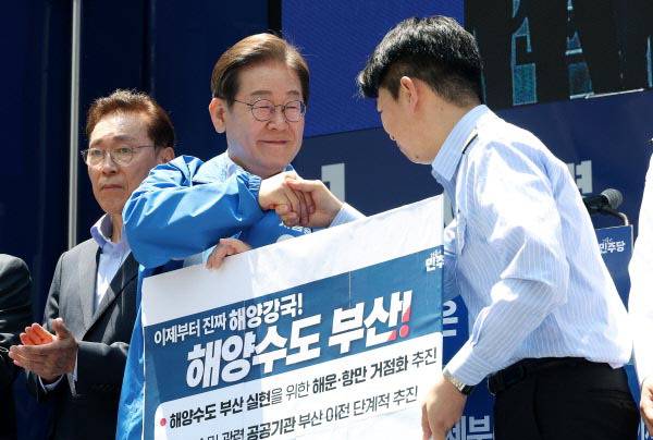 이재명 더불어민주당 대선 후보가 지난 14일 부산 서면 쥬디스태화 인근에서 부산 유세에 참석해 해양수도 부산 협약서에 서명한 뒤 권기흥 에이치라인해운해상직원노조 위원장과 악수하고 있다. 국제신문 DB