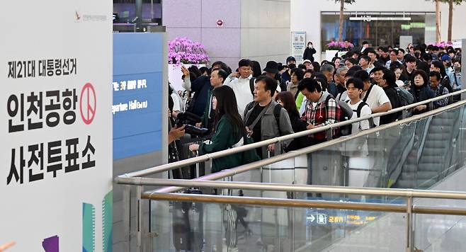 Outbound travelers wait in line to cast early votes at a polling station inside the departures lobby of Incheon Airport on Thursday. (Lee Sang-sub/The Korea Herald)