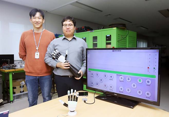 [대전=뉴시스] 기계연구원이 단순한 제어로 고효율·고안정성 파지 기능을 구현할 수 있는 로봇의수 기술을 개발했다. 기계연 신민기(오른쪽) 선임연구원과 안보현 선임기술원이 개발한 로봇의수를 들어보이고 있다.(사진=기계연구원 제공) *재판매 및 DB 금지