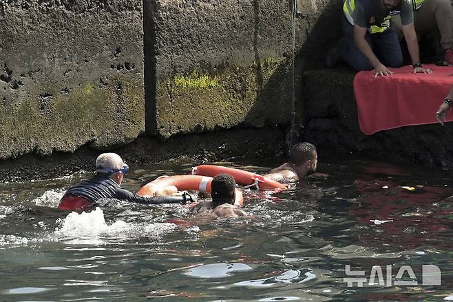[엘이에로=AP/뉴시스] 28일(현지 시간) 스페인 카나리아제도 엘이에로 항구 인근에서 전복된 이민자 보트의 생존자들이 구조되고 있다. 현지 당국은 서아프리카 기니에서 약 180명을 태우고 출발한 이 보트가 항구에 접근하던 중 전복돼 5세 여아 2명 포함 최소 7명의 여성이 숨졌다고 밝혔다. 현지 경찰은 승선자들이 보트 한쪽으로 몰리면서 사고가 일어난 것으로 보인다고 전했다. 2025.05.29.