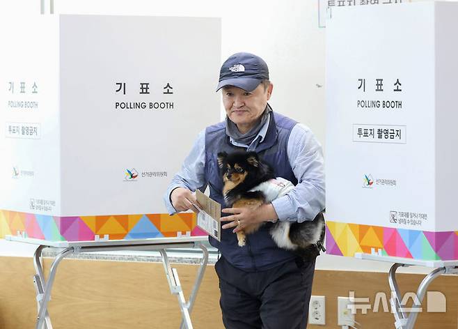 [서울=뉴시스] 김진아 기자 = 제21대 대통령선거 사전투표가 시작된 29일 서울 중구 중림동주민센터에 마련된 사전투표소에서 한 유권자가 강아지와 투표를 하고 있다. 2025.05.29. bluesoda@newsis.com