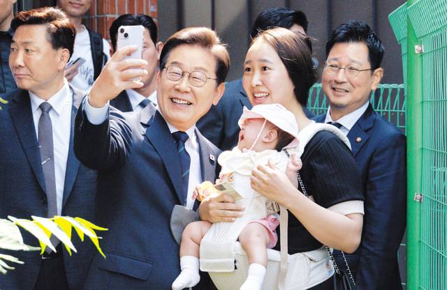 이재명 더불어민주당 대선 후보가 29일 서대문구 신촌동 주민센터에서 사전투표를 마친 뒤 아이를 안고 나온 지지자와 셀카를 찍고 있다. 이병주 기자