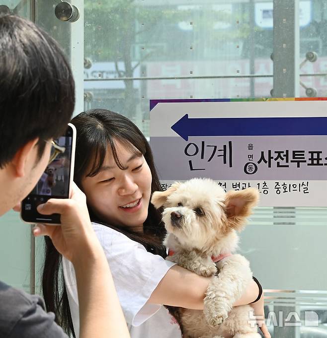[수원=뉴시스] 김종택 기자 = 제21대 대통령선거 사전투표 둘째날인 30일 경기 수원시청 별관에 마련된 사전투표소에서 투표를 마친 한 유권자가 반려견과 함께 인증샷을 촬영하고 있다. 2025.05.30. jtk@newsis.com