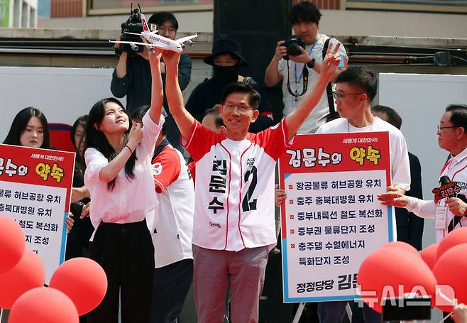 [충주=뉴시스] 고승민 기자 = 김문수 국민의힘 대선 후보가 30일 충북 충주 젊음의거리에서 유세를 하기 전 청년 참가자에게 '항공물류 허브공항' 메시지가 적힌 모형 비행기를 들고 포즈를 취하고 있다. 2025.05.30. kkssmm99@newsis.com