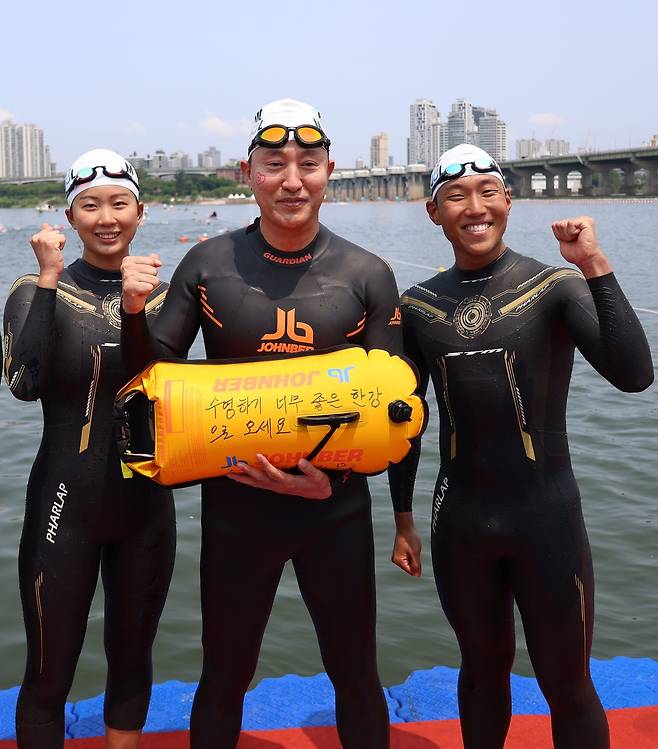 오세훈 서울시장이 30일 광진구 자양동 뚝섬한강공원에서 ‘쉬엄쉬엄 한강 3종 축제’ 1일차 수영종목에 출발 전 ‘수영하기 너무 좋은 한강으로 오세요 수질 환상적!’ 안전부이를 들고 도강을 준비하고 있다. 서울시 제공