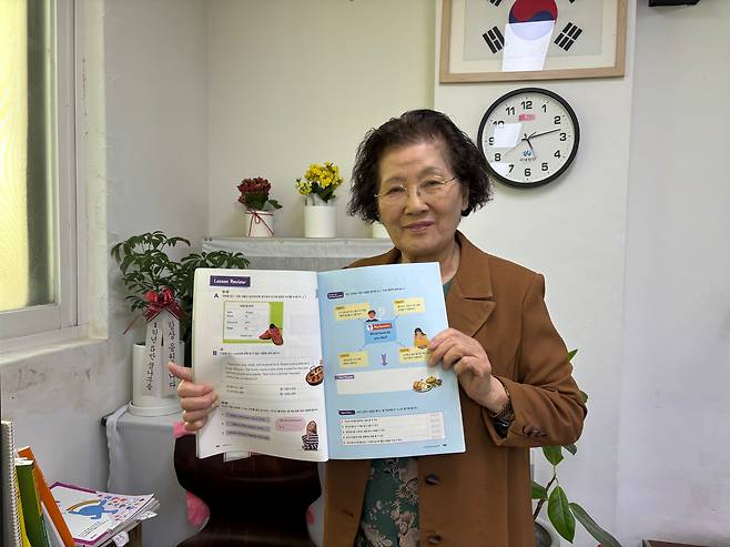 정숙자씨가 일성여중 교실에서 영어책을 펼치며 웃고 있다. /최하연 기자