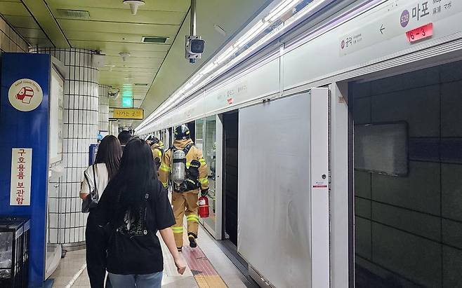 31일 오전 8시 47분께 서울 지하철 5호선 여의나루에서 마포역 방향으로 향하던 지하철에서 방화로 인한 화재가 발생해 승객들이 철로에서 내려 마포역으로 대피하고 있다. 독자제공·뉴시스