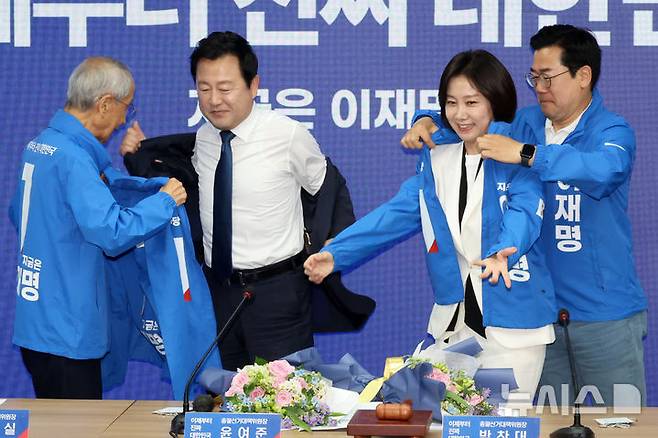 [서울=뉴시스] 조성우 기자 = 윤여준(왼쪽), 박찬대 더불어민주당 상임총괄선대위원장이 26일 오전 서울 여의도 중앙당사에서 열린 입당 환영식에서 김용남(왼쪽 두 번째부터) 전 의원과 허은아 전 개혁신당 대표에게 선거운동복을 입혀주고 있다. 2025.05.26. xconfind@newsis.com