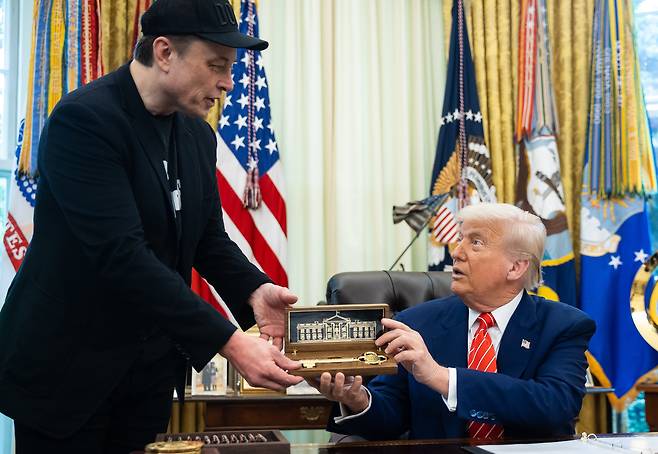 도널드 트럼프 미국 대통령이 지난달 30일 워싱턴 DC 백악관 오벌 오피스에서 열린 기자회견 중 일론 머스크 테슬라 최고경영자에게 '황금 열쇠'를 전달하고 있다./EPA 연합뉴스