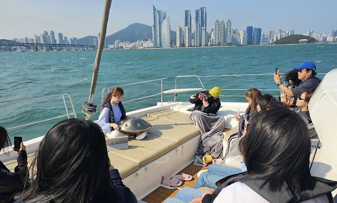 부산 해운대 더베이 101에서 진행된 '요트 리트릿' 프로그램 현장. 핸드팬 아티스트 안유진씨(맨 뒤)가 요트 선상에서 핸드팬 연주를 선보이고 있다. 사진=변옥환 기자