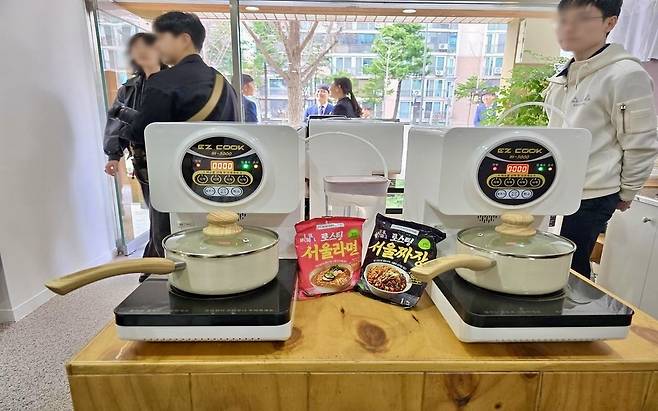 Cooking pots on electric burners are seen next to Seoul-branded instant noodles at a self-serve food station in the Seoul Maeum Convenience Store. The space allows visitors to have a free meal and access mental health support in a low-pressure, welcoming environment. (Seoul Metropolitan Government)