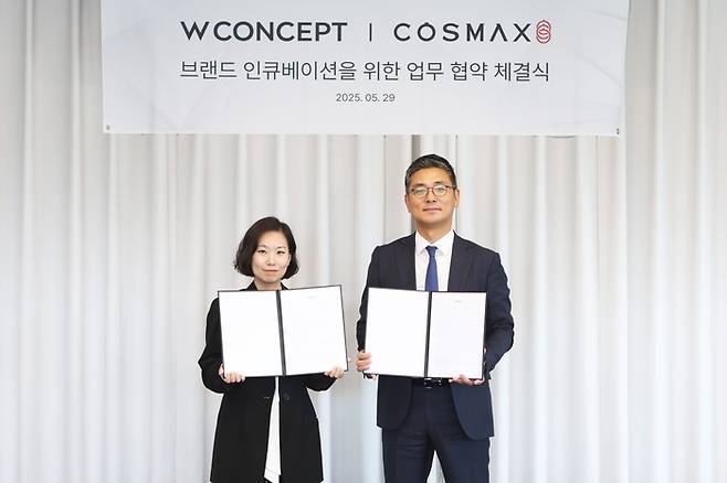 안지수 W컨셉 상품기획담당(왼쪽)과 최재우 코스맥스 국내마케팅본부 부문장(오른쪽)이 업무협약 체결 후 기념사진을 촬영하고 있다.