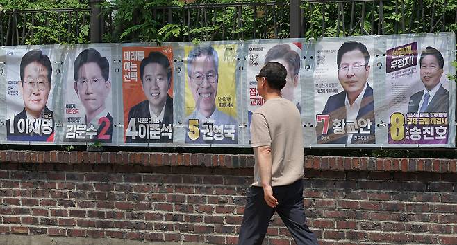 A pedestrian walks in front of a display of presidential campaign posters at Jongno-gu, central Seoul, Sunday. (Yonhap)