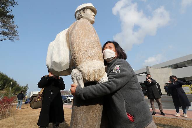 The mother of 25-year-old Kim Yong-gyun, a non-regular subcontracted worker who died at the Taean Thermal Power Plant in South Chungcheong on Dec. 11, 2018, holds a statue of her son set up outside the plant on Dec. 7, 2021. [YONHAP]